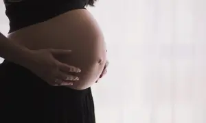 Brzuch kobiety w ciąży, dłonie delikatnie go obejmują. Czas oczekiwania na dziecko, być może pierwsze skurcze przepowiadające.