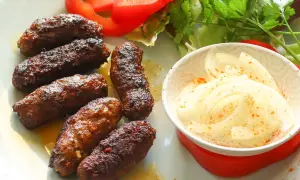 Saftige Cevapcici, perfekt gegrillt, serviert mit Zwiebeln und Salat. Ein tolles Cevapcici Rezept für jeden Anlass.