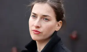 Portret kobiety w czarnym płaszczu, z niebieskimi oczami i rozpuszczonymi włosami. Plan średni.