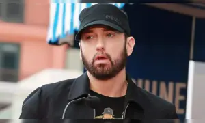 Eminem, znany jako "mockingbird po polsku", w czapce i z brodą, przemawia do mikrofonu.