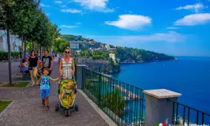 Rodzina spaceruje promenadą, podziwiając piękne widoki na morze i miasto. To idealne miejsce na odkrywanie atrakcji Sorrento.