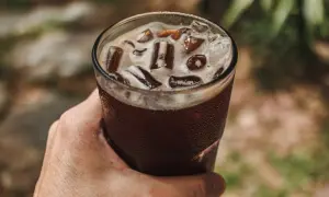 Dłoń trzyma szklankę orzeźwiającego napoju z lodem. To idealny sposób na ochłodę, gdy zastanawiasz się, cold brew co to.