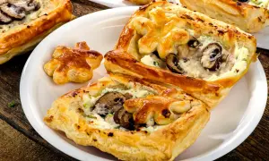 Chrupiące ciasto francuskie z pieczarkami i serem, podane na białym talerzu. Idealne na przekąskę.