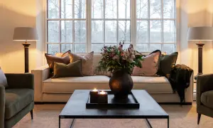 Mysig lounge med soffa och gröna artwood fåtöljer. Blommor, ljus och en filt skapar en varm atmosfär.