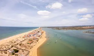 Faro: Was tun? Eine Küstenstadt mit Sandstrand, Häusern und vielen Booten im Wasser. Perfekt für einen entspannten Urlaub.
