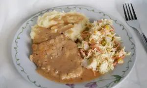 Schab duszony z cebulą w sosie własnym, podany z puree ziemniaczanym i surówką z kapusty. Pyszny, domowy obiad.