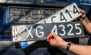Ręce wymieniają tablice rejestracyjne. Jedna z nich, z numerem KXG 4325, jest przykręcana. To ważny etap w procesie rjs rejestracja.