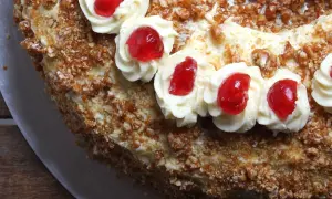 Ein köstlicher Frankfurter Kranz mit Buttercreme-Tupfern und roten Kirschen, umhüllt von knusprigen Mandelsplittern.
