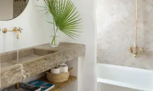 Elegante lavabo de piedra natural y grifería dorada, parte de una cuidada decoracion cuartos de baño con azulejos de escamas.