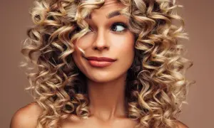 Kobieta z burzą blond loków do ramion. Jej fryzury włosy kręcone do ramion dodają jej uroku.