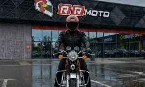 Motocyklista w kurtce z membraną, która chroni przed deszczem, przed budynkiem RR MOTO.