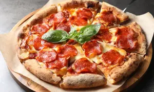 En napolitansk pizza med generöst med pepperoni som topping, toppad med färsk basilika.