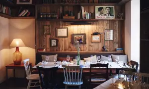 Gemütliche Atmosphäre in einem der besonderen Restaurants Berlins. Holzwände, Bücherregale und ein gedeckter Tisch laden zum Verweilen ein.