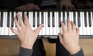 Ręce na klawiaturze fortepianu, rozpoczyna się nauka gry na pianinie.