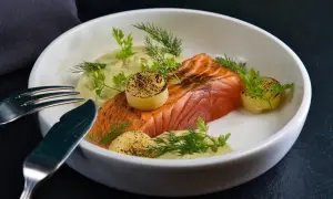 Un délicieux saumon à la toscane, servi avec une sauce crémeuse, des pommes de terre grillées et des herbes fraîches.