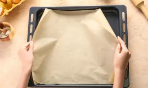 Ręce układają papier do pieczenia na blasze. Zastanawiasz się, czym zastąpić papier do pieczenia?