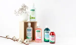 Zestaw płynów do płukania jamy ustnej GUM, w tym ActiVital, Original White, SensiVital+ i Paroex, obok delikatnych kwiatów.