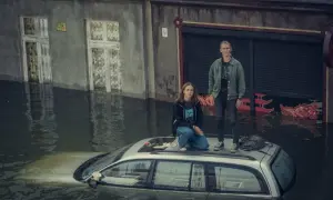 Dwie kobiety na dachu samochodu w zalanej ulicy. W tle budynki, jakby po katastrofie. To jak "Wielka woda" Maryli Rodowicz, tylko bez śpiewu.