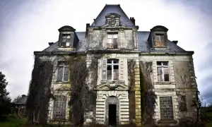 Vaste manoir urbex envahi par la végétation, fenêtres brisées et portes barricadées. Un lieu figé dans le temps, invitant à l'exploration.