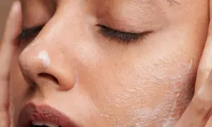 Une femme applique une crème sur son visage. C'est le moment idéal pour savoir quand appliquer crème solaire visage pour une protection optimale.