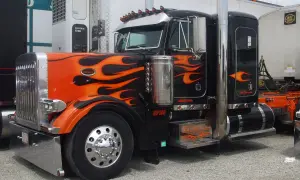 Camion tuning noir et orange avec des flammes, prêt pour la nuit.