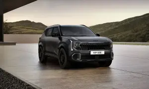 Nowy Kia Seltos w ciemnym kolorze, zaparkowany przed nowoczesnym budynkiem z widokiem na góry.