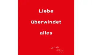Rode achtergrond met witte tekst: "Liebe überwindet alles". Een boodschap dat liefde overwint alles, met een kleine handgeschreven tekst en logo rechtsonder.