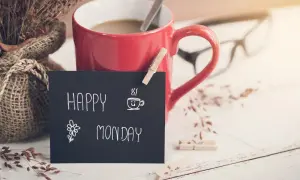 Czerwony kubek kawy, bukiet suszonych traw i tabliczka z napisem "Happy Monday" zapowiadają nowy tydzień.