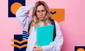 Zmartwiona uczennica w okularach trzyma książkę na tle różowej ściany z geometrycznymi wzorami.