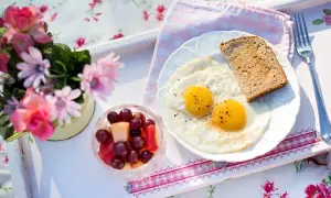 Idealne śniadanie walentynkowe: jajka sadzone, tost i owocowa sałatka. Romantyczny początek dnia.