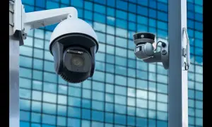 Deux caméras de vidéosurveillance entreprise montées sur un poteau, avec un bâtiment moderne en arrière-plan.