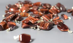 Mnóstwo błyszczących wisiorków z kamienia bawole oko, każdy z metalowym kółeczkiem do zawieszenia.