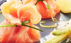 Une délicieuse entrée froide : des fagots d'asperges et de saumon fumé, ornés d'une touche de citron et de ciboule.