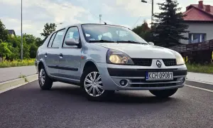 Srebrny Renault Thalia 1.4 z polskimi tablicami rejestracyjnymi KCH 09081 zaparkowany na poboczu drogi.