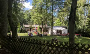 Ein Biergarten im Grünen, mit Gästen an Tischen unter Bäumen und einem Festzelt. Hier findet man **hanffs ruh**.