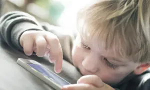 Un enfant blond joue sur un téléphone. Est-ce le wifi ou la 4G le plus dangereux pour lui ?