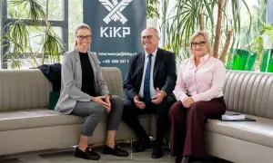 Trzy osoby siedzą na kanapie przed banerem z logo KiKP.