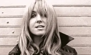 Młoda Maryla Rodowicz z burzą blond włosów i w skórzanej kurtce, pozuje na tle drewnianej ściany.
