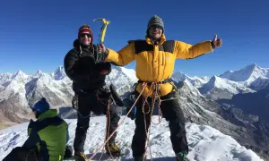 Dwóch alpinistów na szczycie Mera Peak, jeden z czekanem, drugi z kciukiem w górę. W tle ośnieżone góry.