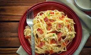 Pyszne spaghetti carbonara z chrupiącym boczkiem, posypane natką pietruszki. Idealne danie, gdy zastanawiasz się nad spaghetti carbonara kcal.
