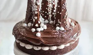Una magica torta di Natale al cioccolato, decorata con alberelli innevati e dolci fiocchi di neve.