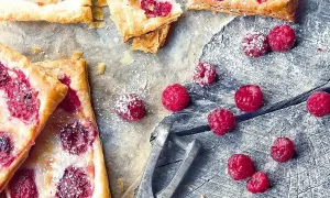 Pyszne ciasto francuskie z malinami, posypane cukrem pudrem. Ile piec ciasto francuskie? Krótko, by było chrupiące!