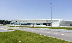 Nowoczesny budynek lotniska Lublin Airport w Świdniku. Widok na parking i drogę prowadzącą do terminala, gdzie oczekiwane są przyloty.