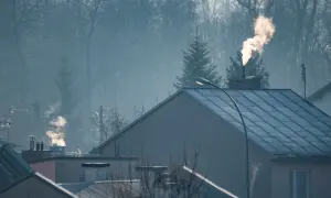 Dym z komina nad domami, czy spaliny z pieca gazowego są szkodliwe? Mglisty poranek nad miastem.