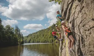 Grupa przyjaciół pokonuje via ferrata w Czechach, wspinając się po skalnej ścianie nad malowniczą rzeką.