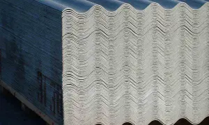Lastra ondulata in fibrocemento ecologico, impilata su pallet. Materiale da costruzione resistente e durevole.