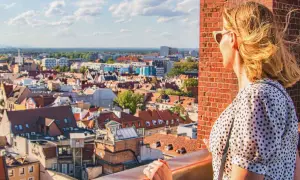 Kobieta podziwia panoramę Wrocławia, planując, co zobaczyć w 1 dzień. Widok na dachy kamienic i niebo.