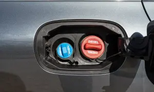 Dwa korki wlewu paliwa w samochodzie: niebieski z napisem AdBlue i czerwony z napisem Diesel.