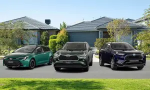 Trzy modele toyoty crossover: zielona Corolla Touring Sports, ciemnozielony Highlander Hybrid i granatowy RAV4 Plug-in Hybrid, stoją przed domami.