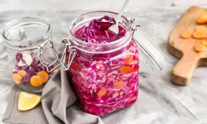 Roter Kohl und Karotten in Gläsern, bereit zum Kohl haltbar machen. Ein Löffel ragt aus dem vorderen Glas.